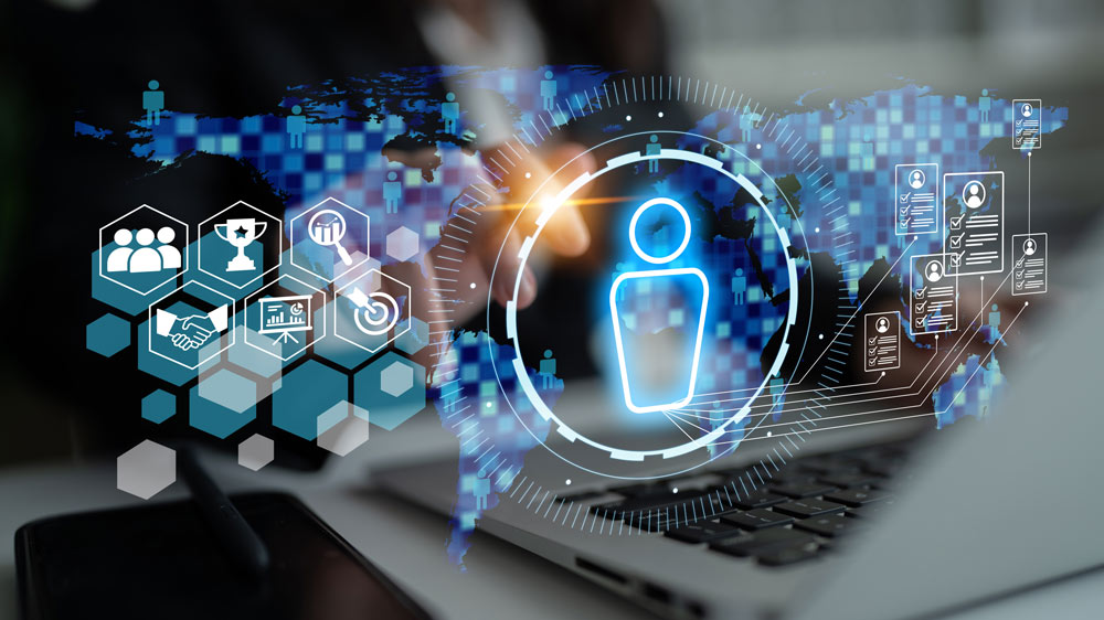 Person at a laptop with holographic visuals of a person icon and other tech elements across the screen