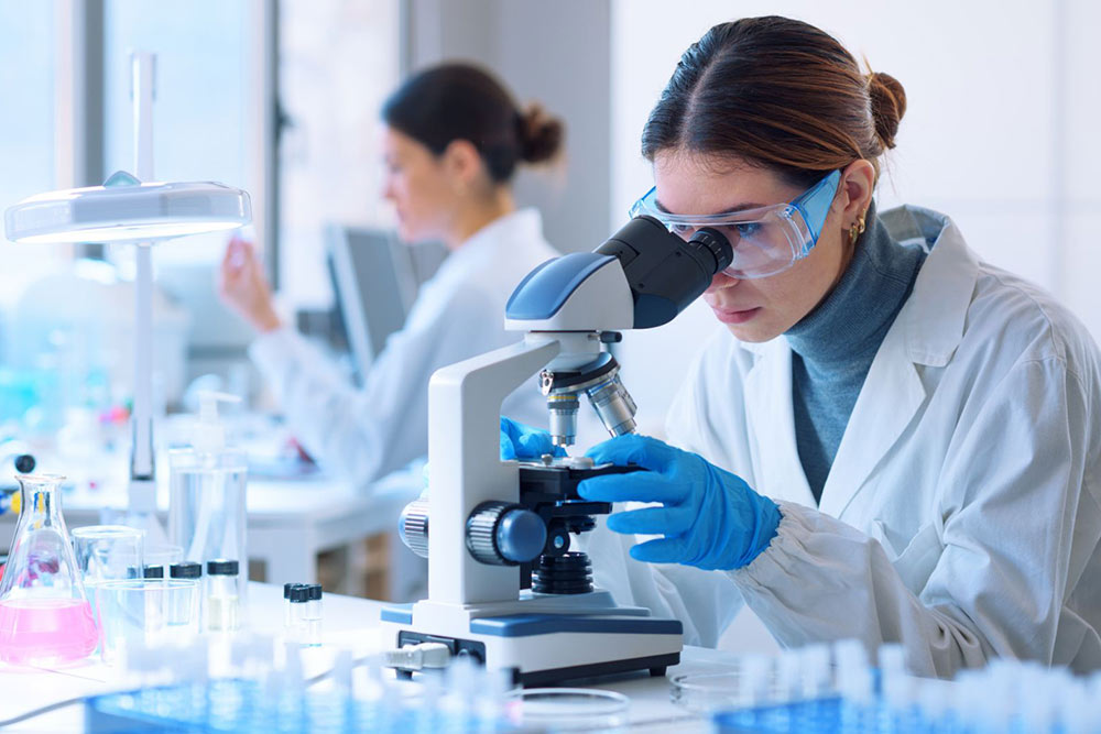 Woman in a lab looking through a microscope